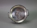 a silver plate on a stand on a gray surface