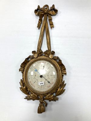 une horloge en or accrochée au mur, sur laquelle est représenté un oiseau