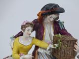 a figurine of a man and a woman with a bird in a cage