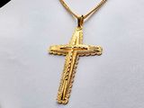 a close up of a gold cross necklace on a mannequin