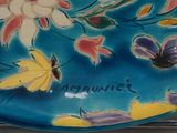 a blue plate with flowers and butterflies painted on it