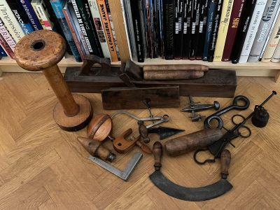 a lot of old tools on the floor in front of a bookcase