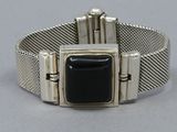 a close up of a silver bracelet with a black stone in the center