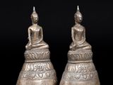 a pair of silver buddha statues sitting on top of each other