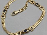 a gold chain bracelet with blue stones on it