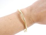a woman ' s arm with a gold bracelet on it