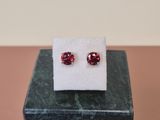 a pair of red ruby stone stud earrings sitting on top of a marble block