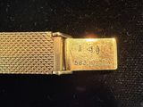 an image of a close up of a gold watch on a black surface