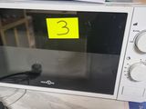a microwave that is sitting on a table with a yellow sticker on it