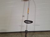 an orange string trimmer sitting on top of a floor next to a garage door