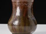 a brown vase that is sitting on a white table