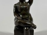 statue of a woman sitting on a stool with her hand on her head