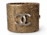 a close up of a gold bracelet with a chanel logo on it