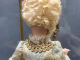 une poupée aux cheveux blonds, vêtue d'une robe et d'un col en dentelle