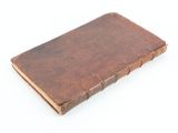 an old book is sitting on a white surface with a white background