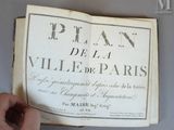 quelqu'un tient un livre ouvert à une page sur laquelle figure une photo de Paris
