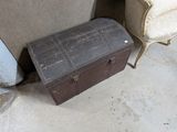 une vieille malle posée à côté d'une chaise dans une pièce
