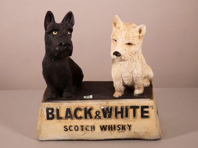 deux figurines représentant des chiens noir et blanc assis sur une boîte