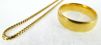 a gold ring and a gold chain on a white surface
