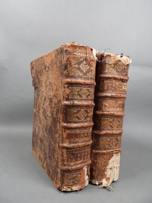 two old books sitting on top of each other on a gray surface
