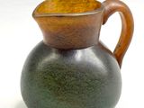 un vase vert avec une anse marron sur un fond blanc