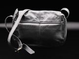 black leather cross body bag on a black background