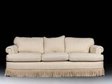 a white couch with fringes on it in a dark room