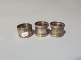 three silver napkin rings sitting on top of a white table