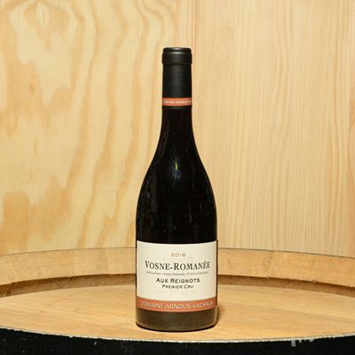 a bottle of wine sitting on top of a barrel