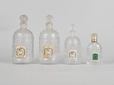 quatre bouteilles en verre sont alignées sur une surface blanche