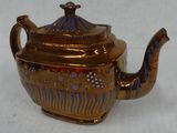 a gold teapot with a blue and red design on it