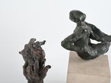 two sculptures of a man and a woman sitting on a rock