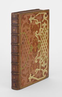 Un vieux livre orné d'un motif décoratif repose sur une surface blanche