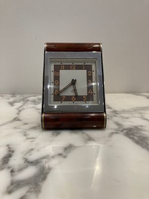 a small clock sitting on top of a marble table