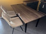 a table with two chairs and a refrigerator in the background