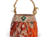 an orange and gold purse with a snake handle on a white background