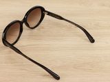 sunglasses on a wooden surface with a black frame and brown lens