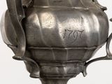 a silver vase that has a handle on it
