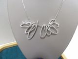 necklace made of silver wire with a leaf design on a mannequin