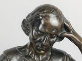 a bronze statue of a man sitting on a bench