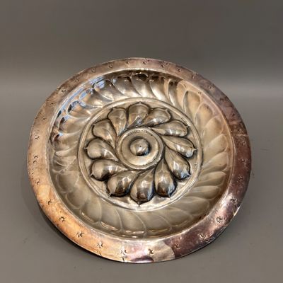un plateau en argent orné d'une fleur, posé sur une table