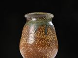 a brown and green vase sitting on top of a table