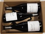 three bottles of wine are in a cardboard box on a table