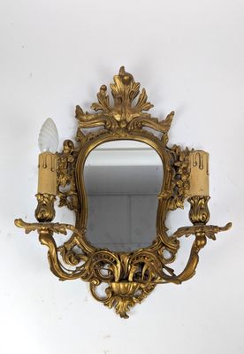 un miroir doré richement décoré, orné de deux bougies et d'un bougeoir