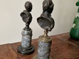 pair of antique bronze busts on marble bases on a wooden table