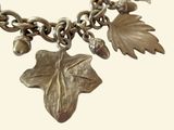 a silver bracelet with a leaf and acorns on it