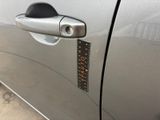 the door handle of a silver car with a sticker on it