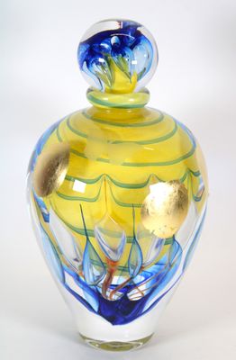 un vase en verre jaune et bleu posé sur une surface blanche