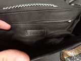 a person holding a black purse with a chain on it