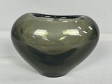 un vase en verre vert posé sur une surface blanche